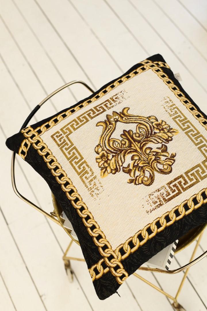 Baroque tapestry pillowcase with gold emblem and chain border placed on a chair