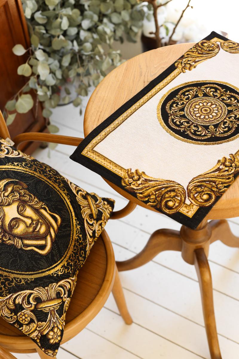 Black and gold Medusa tapestry pillow on a wooden chair
