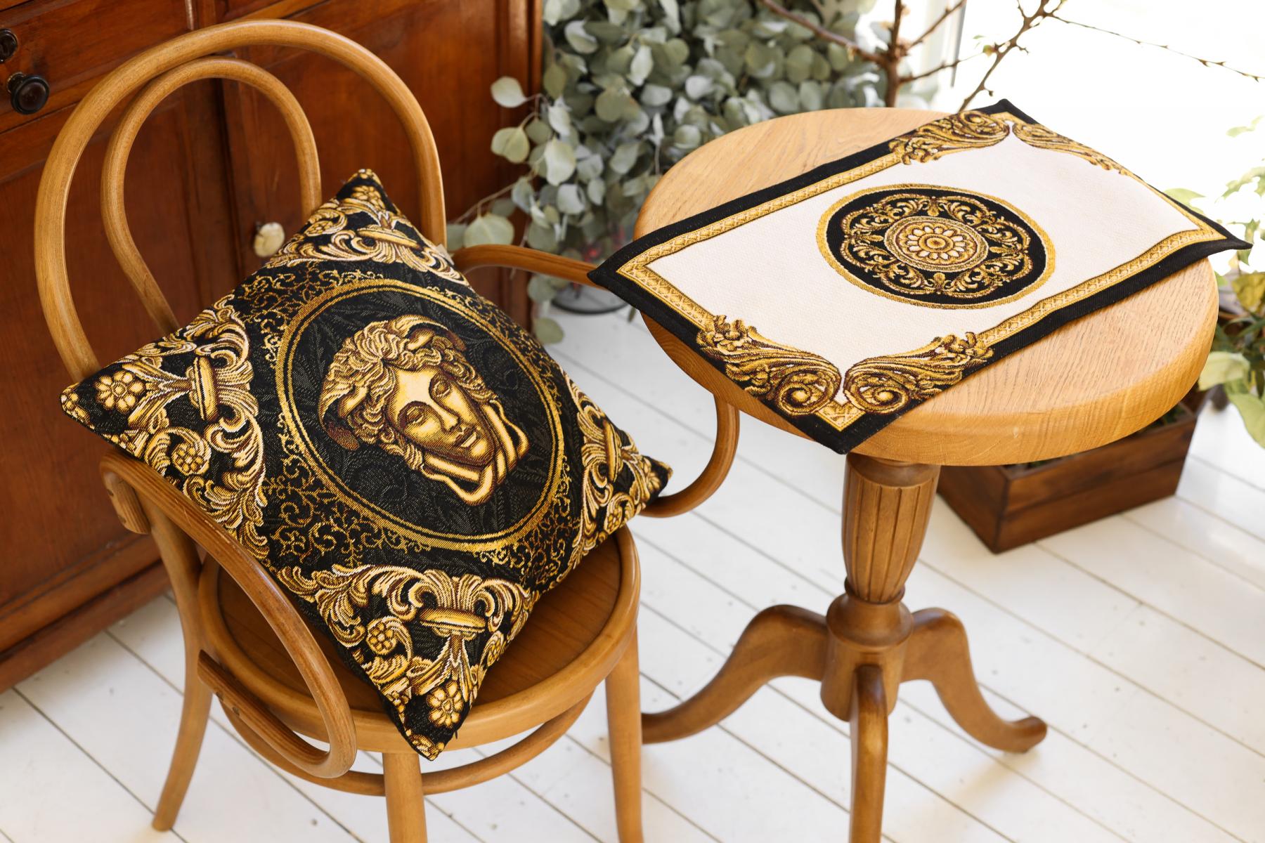 Black and gold Medusa tapestry pillow on a wooden chair