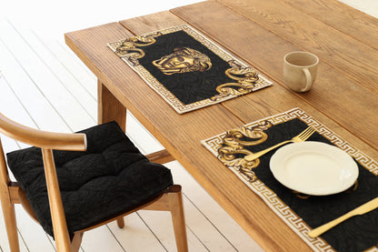 Black baroque chair pad on wooden chair next to dining table with black and gold baroque placemats
