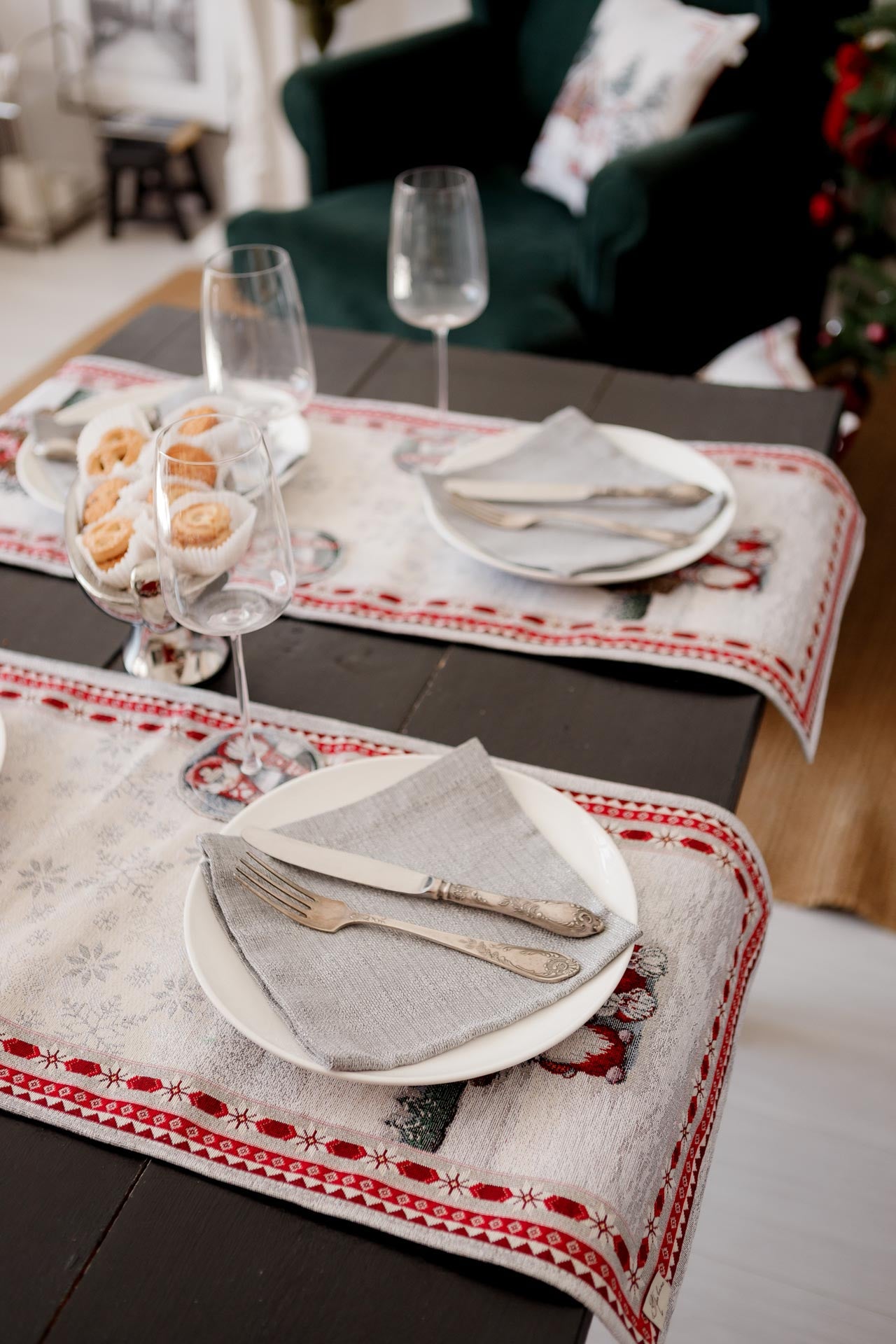 Christmas-themed table runner with gnome pattern under elegant plates and silver cutlery.