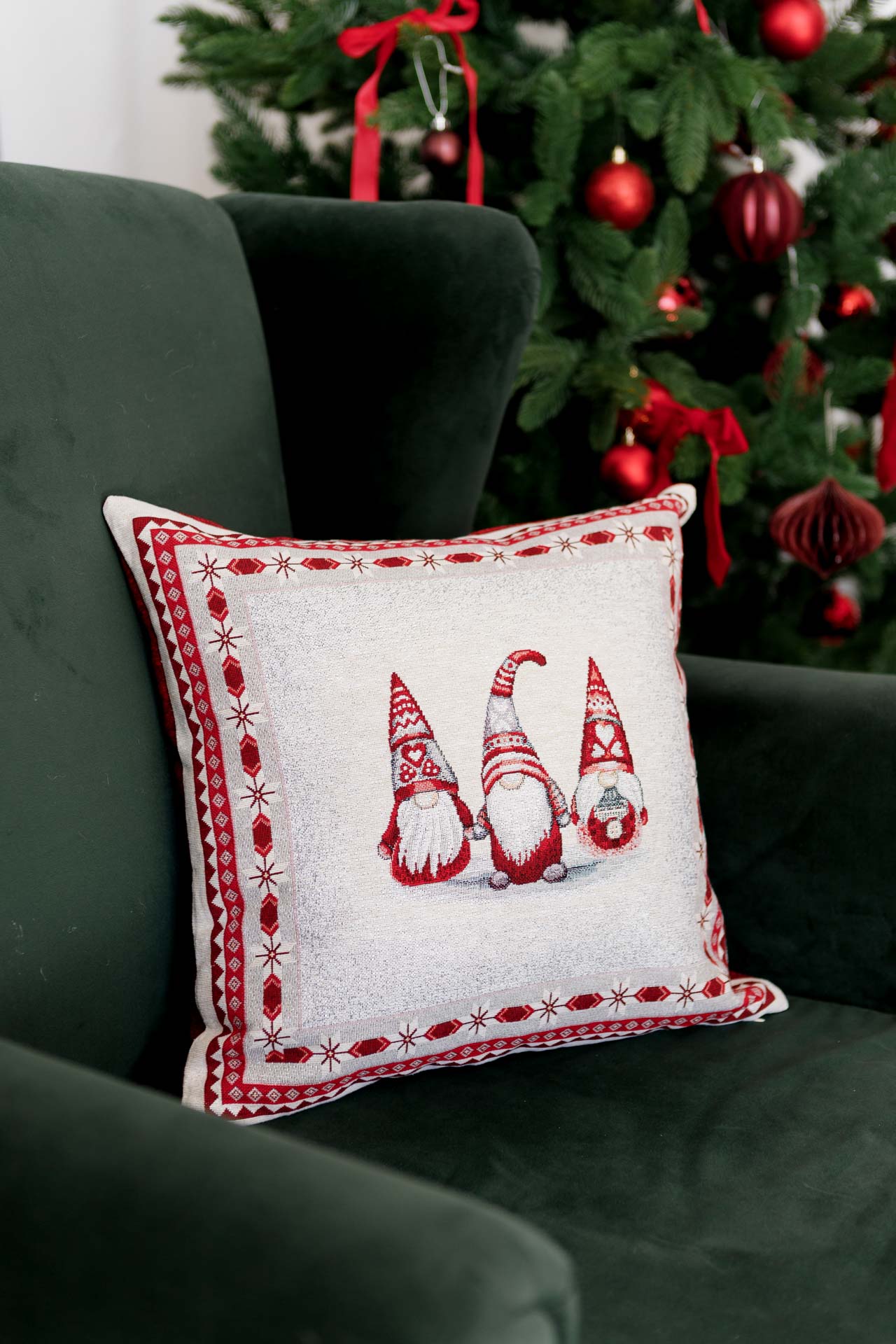 Christmas gnome tapestry pillowcase on a green armchair next to a decorated Christmas tree