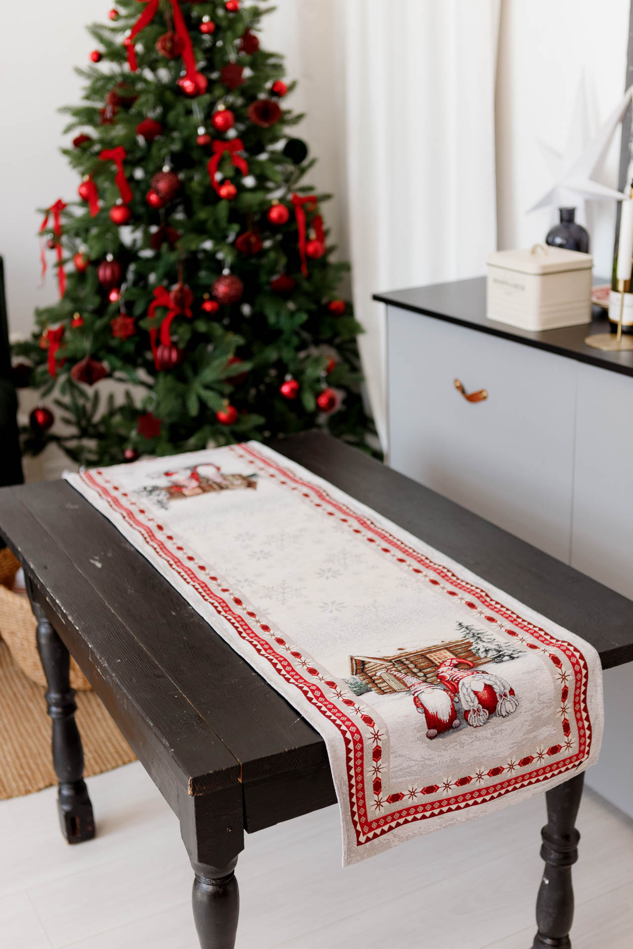 Christmas table runner with gnomes on wooden table, decorated Christmas tree in background, holiday home decor