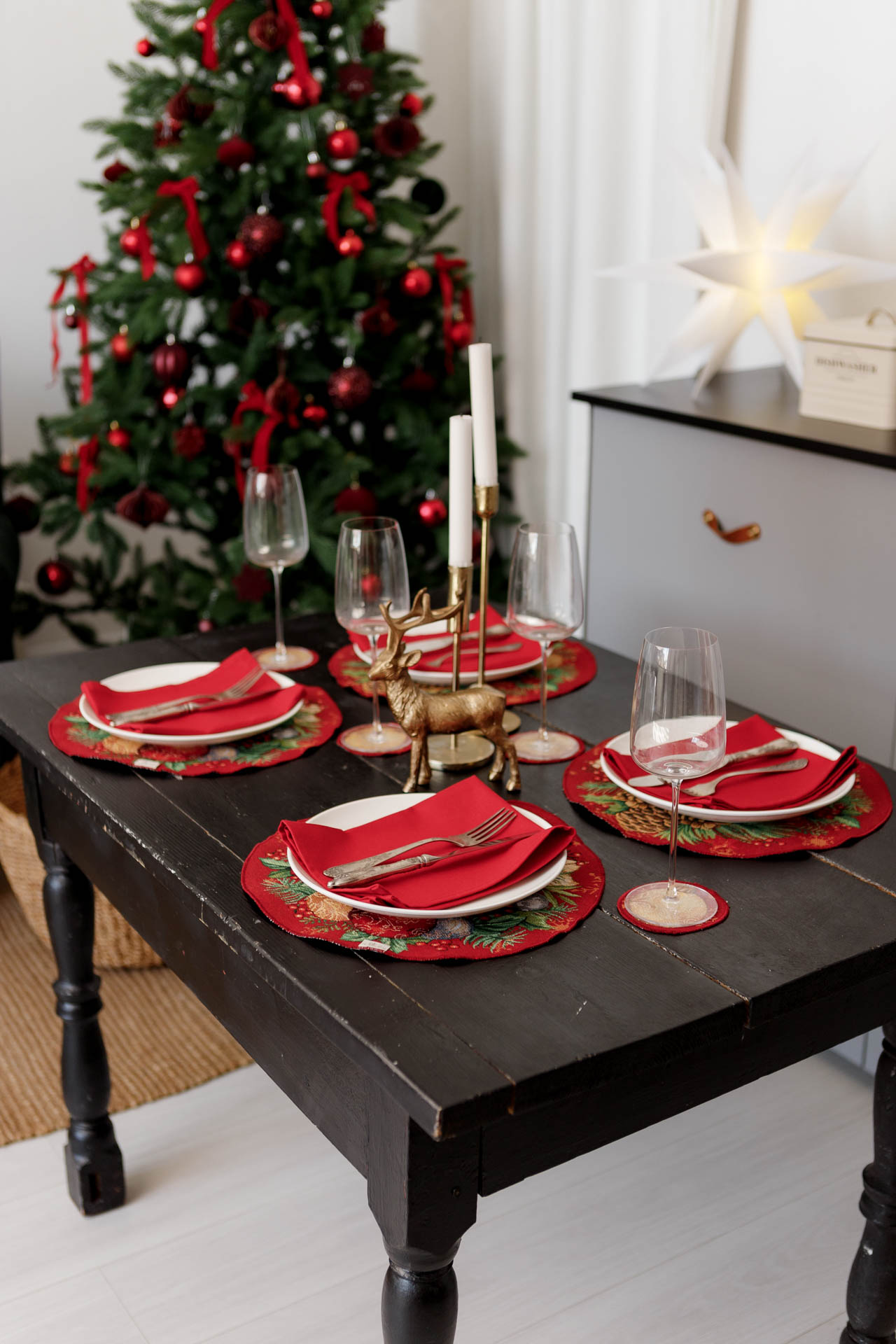 Christmas table setting with round red tapestry placemat and greenery design