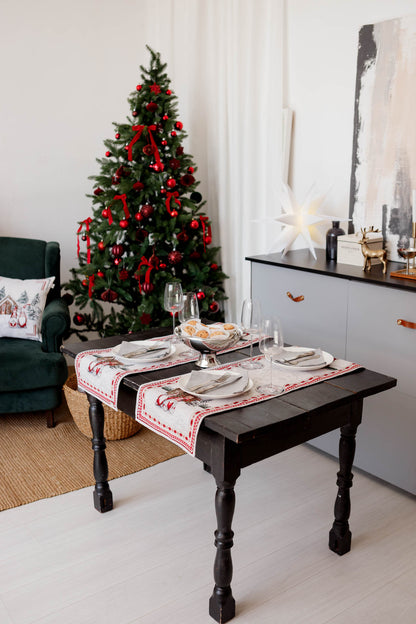 Christmas table setup with gnome tapestry table runners on a rustic wooden table next to a decorated Christmas tree.