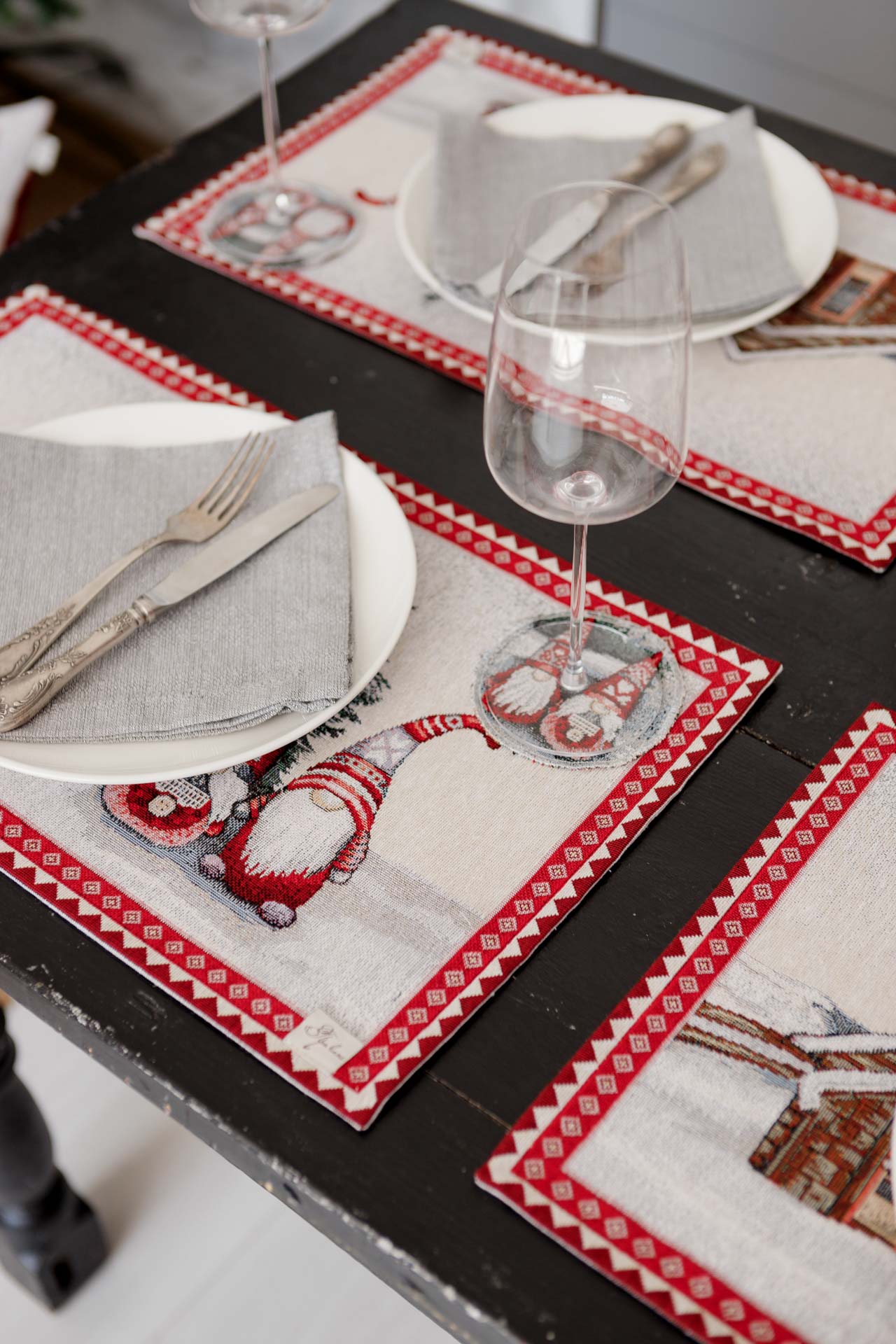 Close-up of Christmas gnome placemat under wine glass and plate with napkin