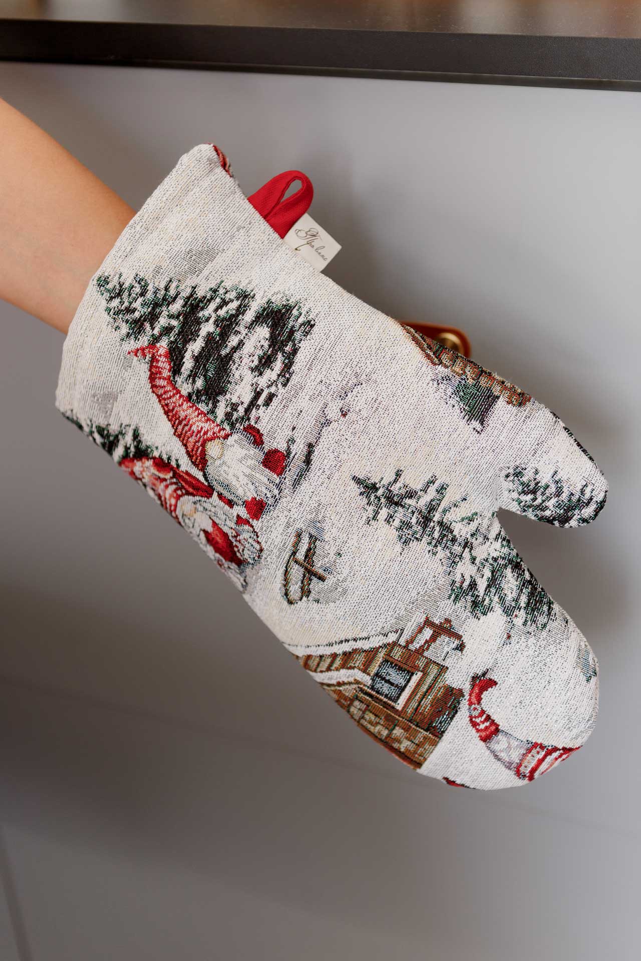 Close-up of Christmas gnome tapestry oven mitt with snowy cottage pattern