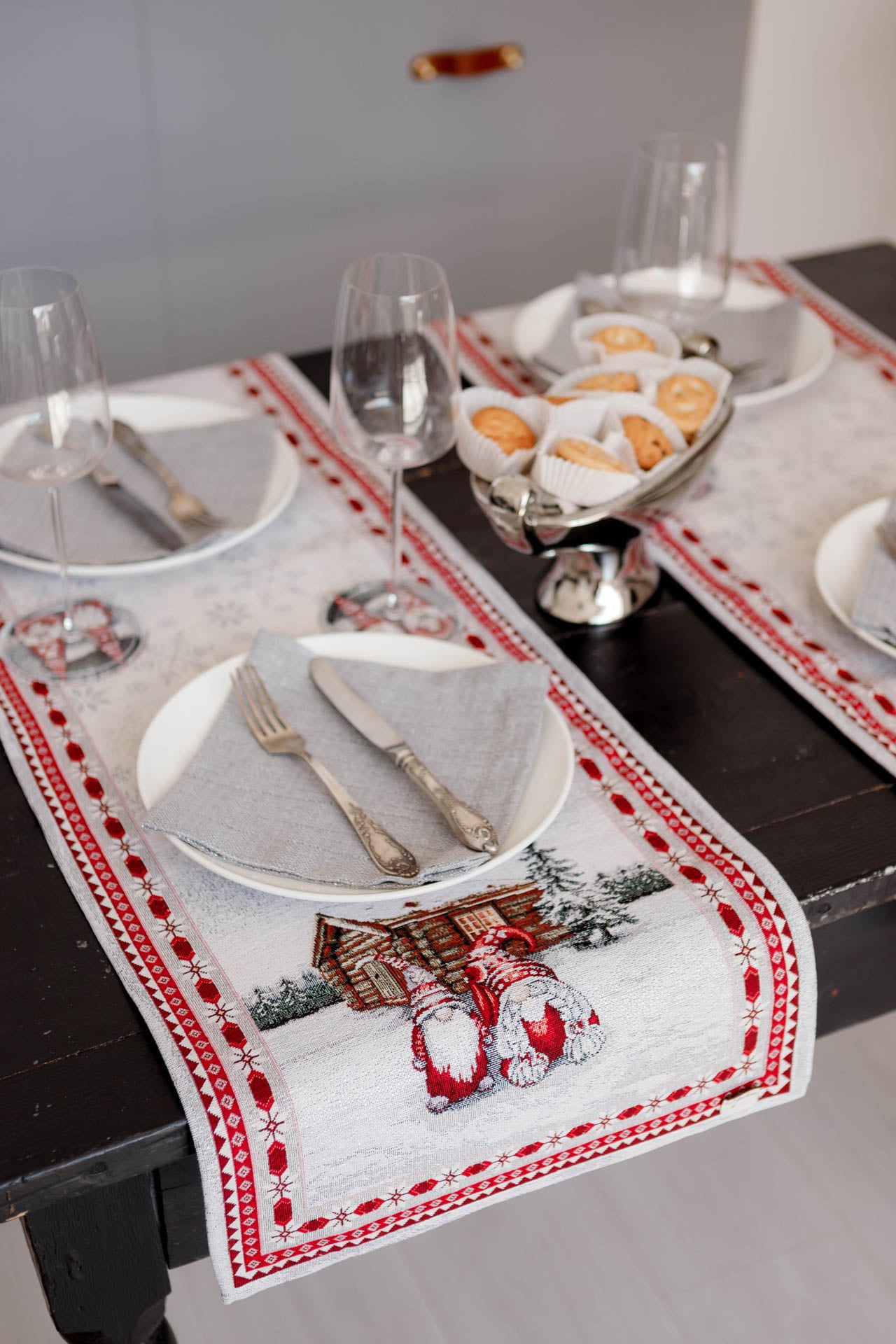 Close-up of Christmas gnome tapestry runner showing winter cottage design under tableware.