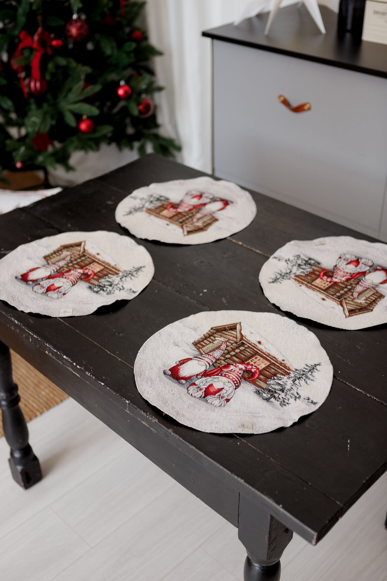 Close-up of Christmas tapestry placemats with gnome and cottage design arranged on dining table