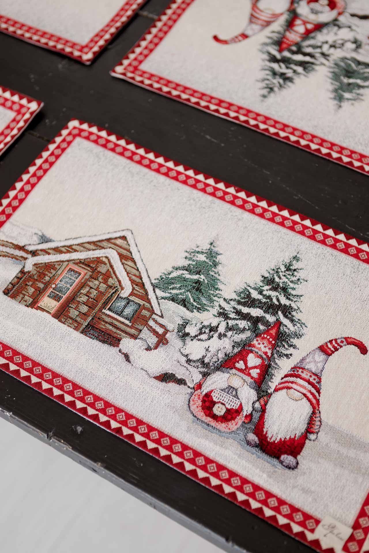 Close-up of Christmas tapestry placemats with red geometric border on wooden table
