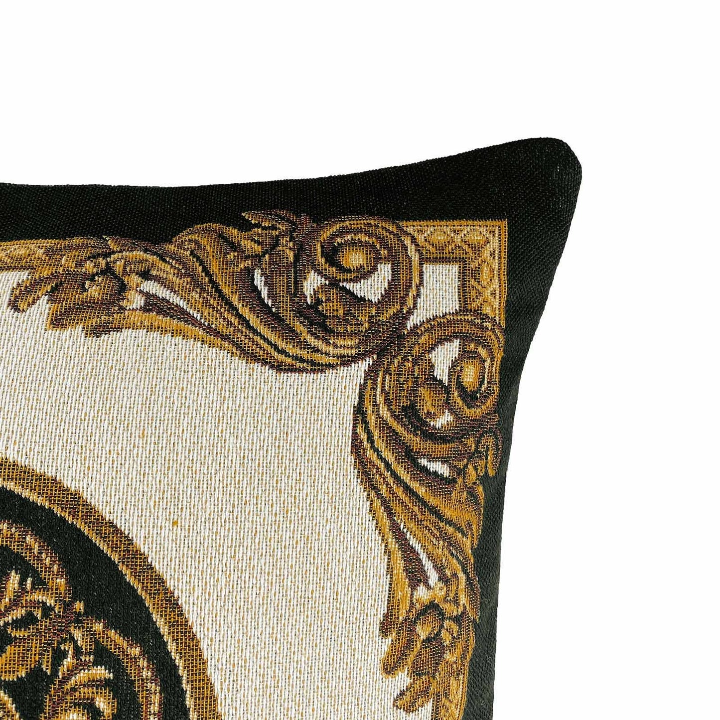 Close-up of a baroque tapestry pillow corner with gold scrollwork pattern on a black and white background