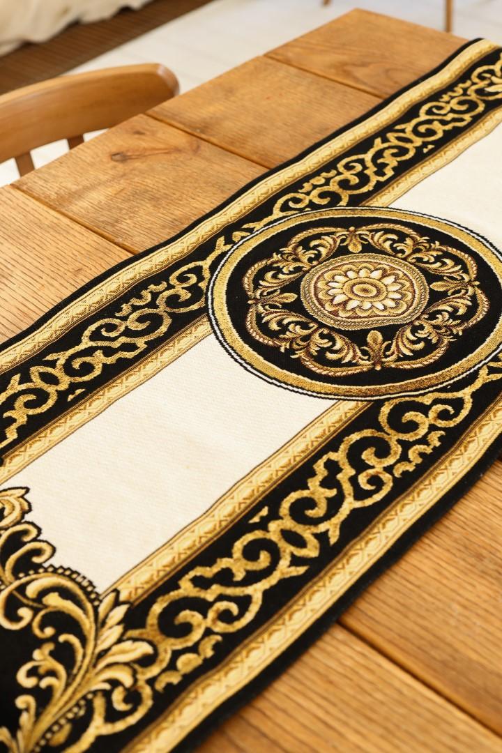 Close-up of a baroque tapestry table runner with intricate gold detailing on a wooden table.