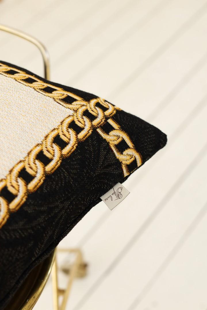 Close-up of baroque tapestry pillowcase corner with gold chain embroidery and woven black detail
