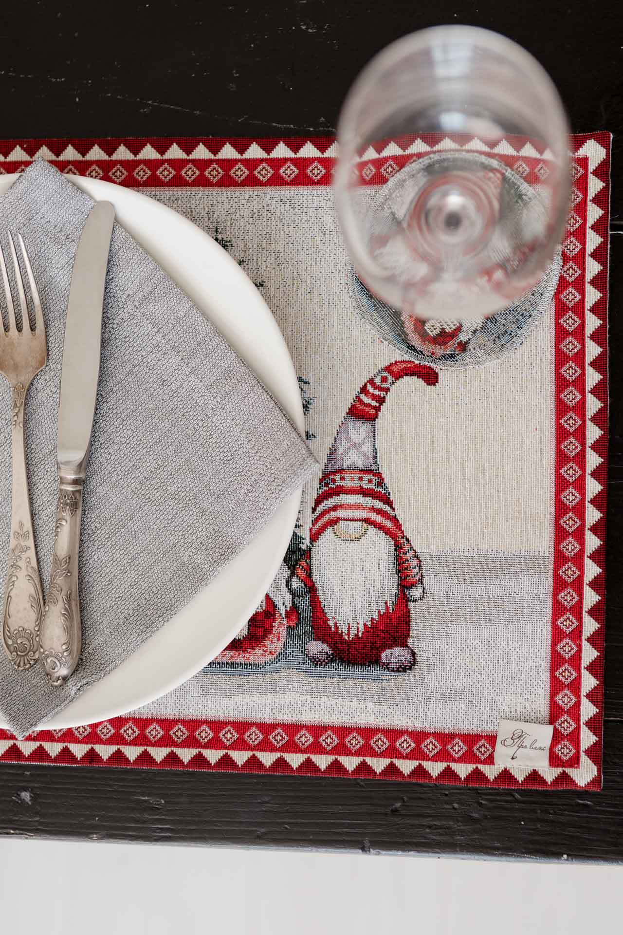 Close-up of detailed woven gnome motif and red border on Christmas tapestry placemat
