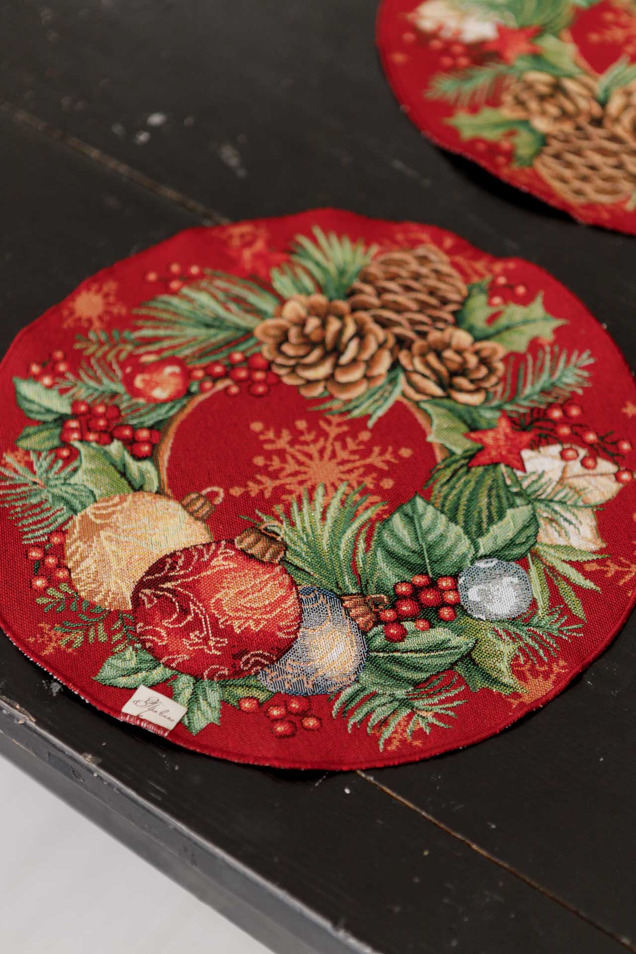 Close-up of red round tapestry Christmas placemat with pinecones and ornaments
