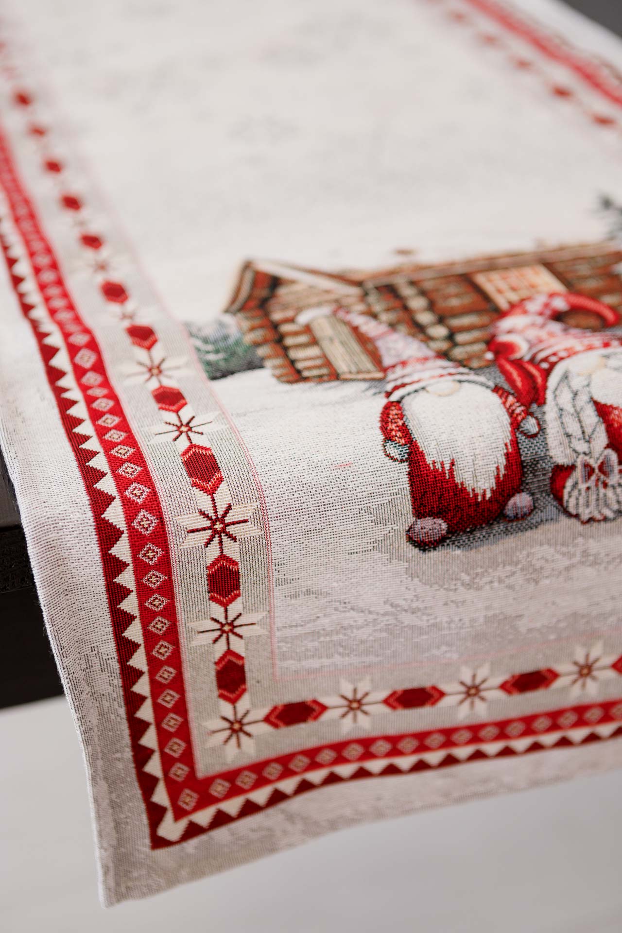 Close-up of woven Christmas gnome table runner showing winter cottage pattern and red accents.