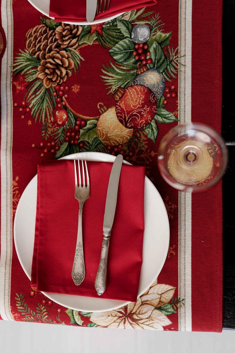 Close-up of woven tapestry fabric with poinsettia flowers, Christmas wreath, and gold ornaments.