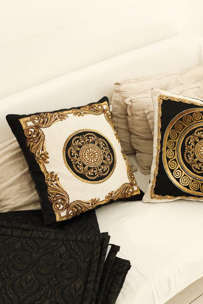 Decorative baroque-style tapestry pillows with gold medallion patterns placed on a light sofa.