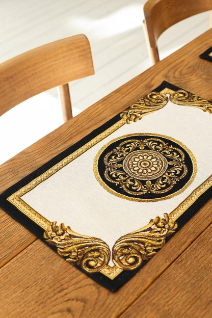 Decorative black and gold baroque-style placemat on a wooden dining table.