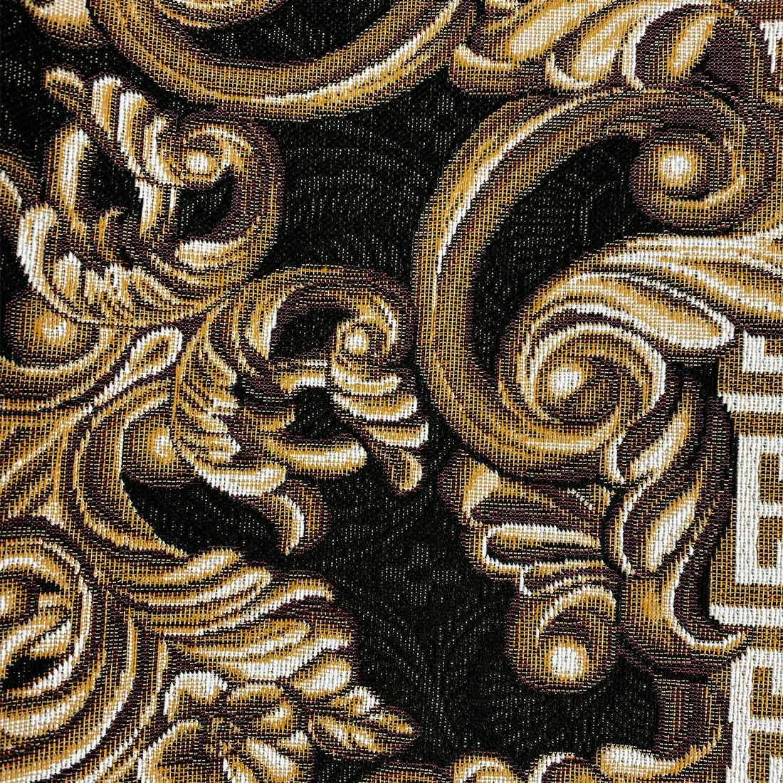 Detailed close-up of ornate gold scrollwork on a black tapestry fabric