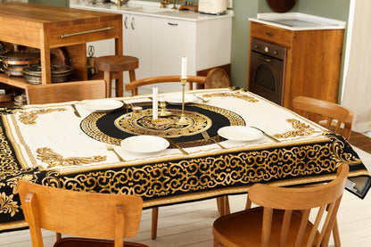 Dining table decorated with baroque gold and black tapestry tablecloth and candles.
