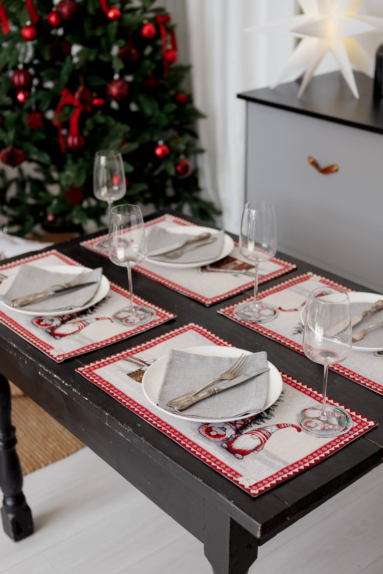 Dining table set with Christmas gnome tapestry placemats, plates, napkins, and wine glasses