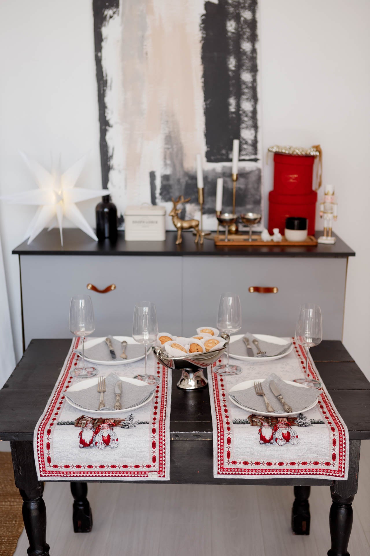 Festive table setting with cookies and wine glasses on Christmas gnome tapestry runner.