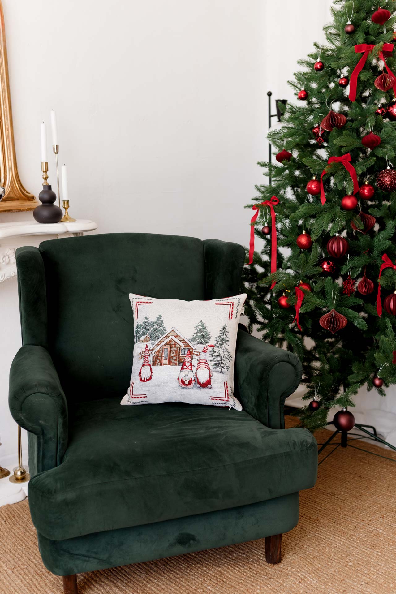 Festive tapestry pillow with gnomes placed on green armchair by decorated Christmas tree
