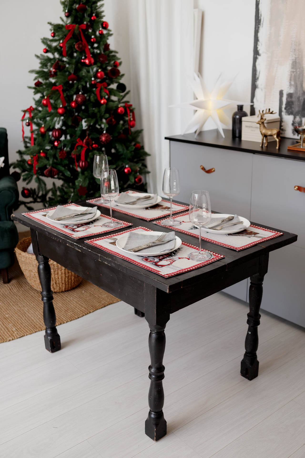 Four Christmas tapestry placemats styled on holiday table next to Christmas tree and modern decor