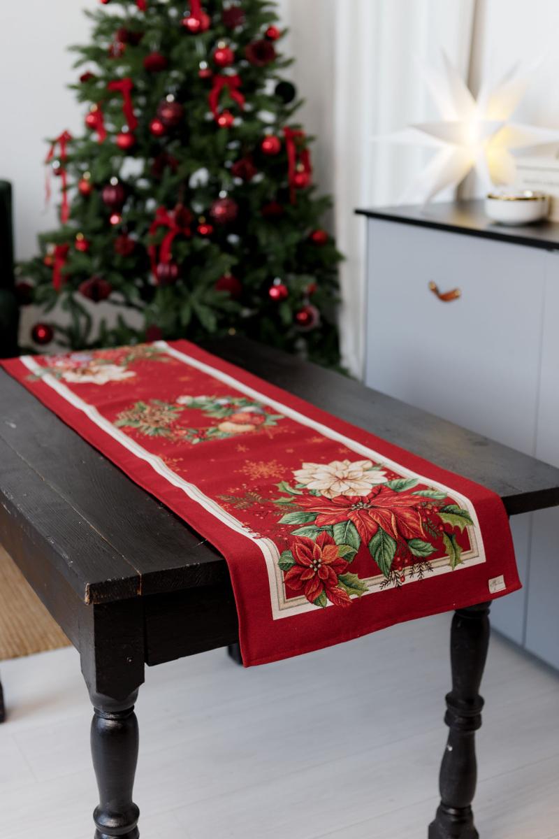 Full view of long red Christmas table runner with poinsettia flower and festive ornament pattern.