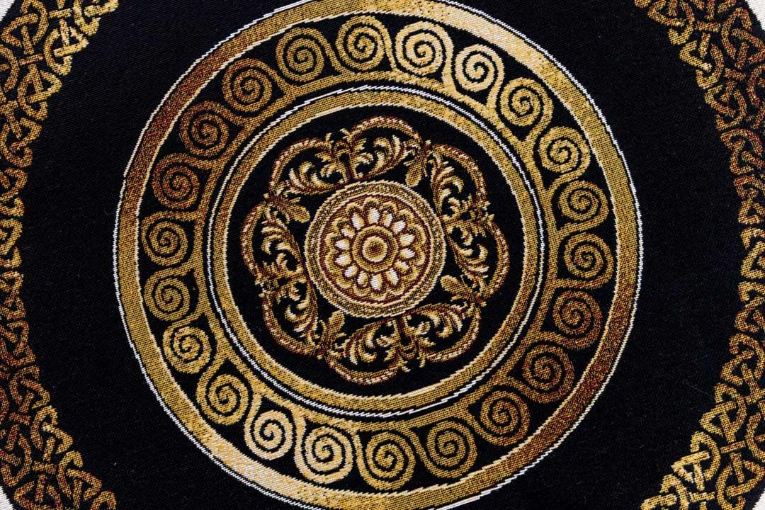 Gold medallion and spiral pattern on black tapestry fabric, detailed macro view.