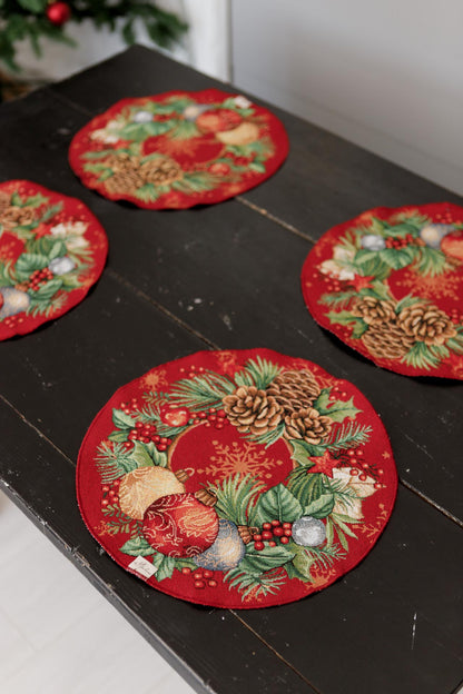 Holiday dining setup with round red tapestry placemat and pinecone motif