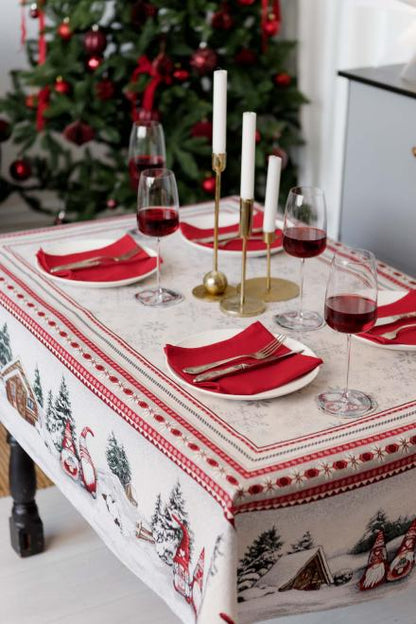 Holiday dinner table set with red napkins and tapestry tablecloth