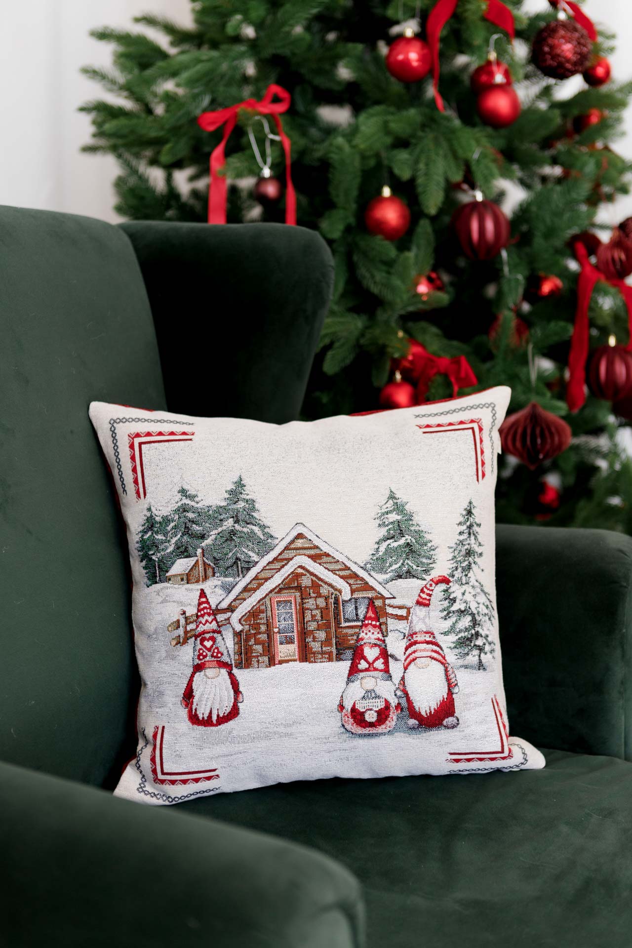Holiday pillowcase with gnomes and winter cabin displayed on green chair next to Christmas tree