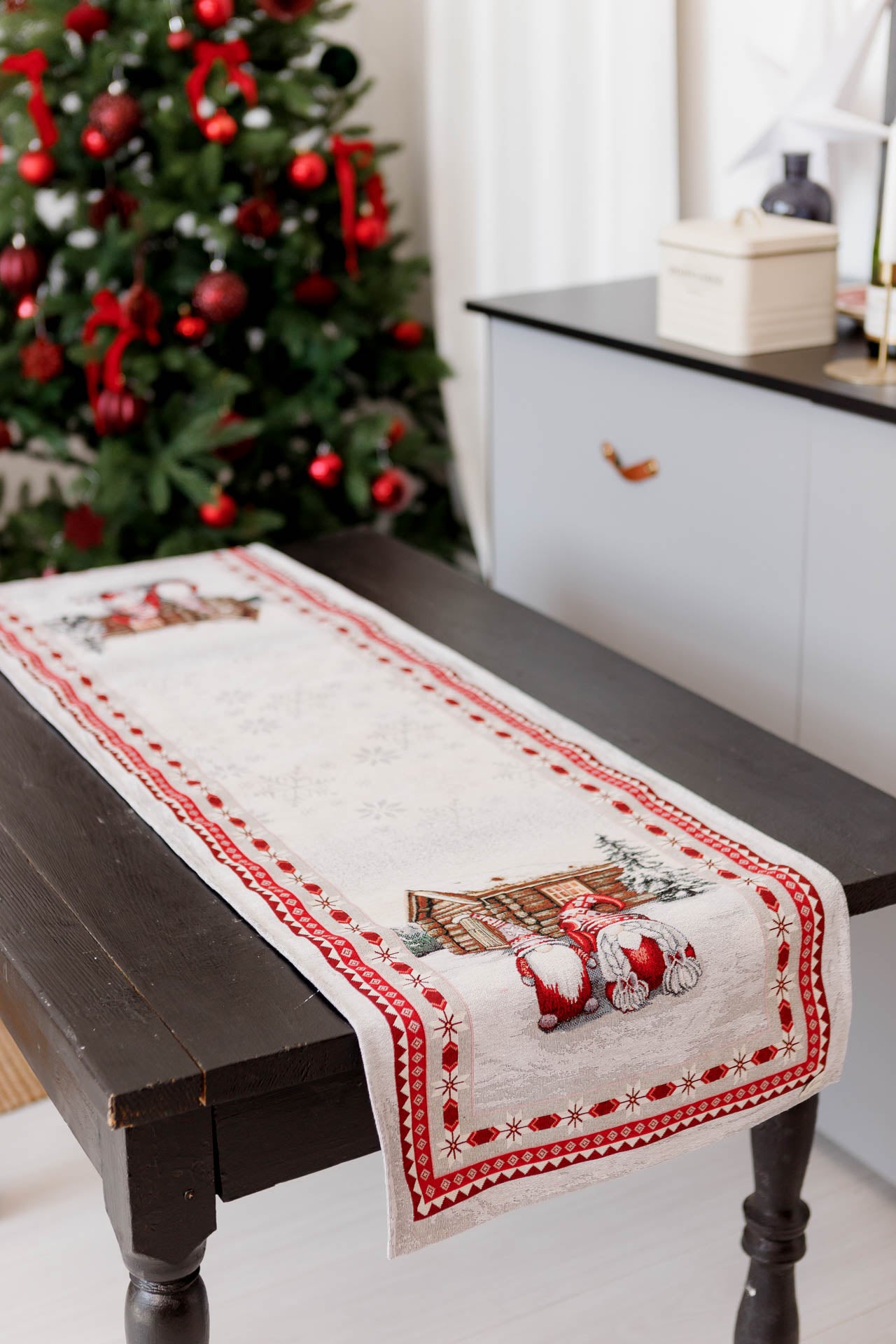 Holiday table runner with gnome design styled on rustic table in festive living room.