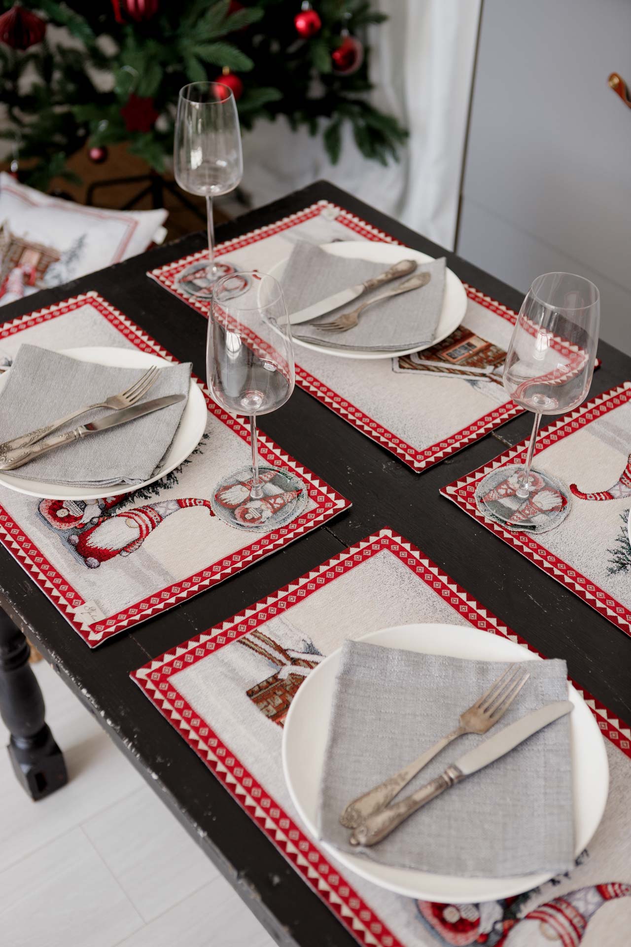 Holiday table setting with gnome tapestry placemats and festive decor in the background