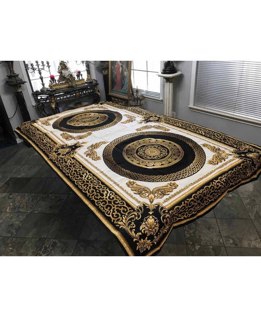 Large baroque tapestry tablecloth with dual gold medallions on dining table.