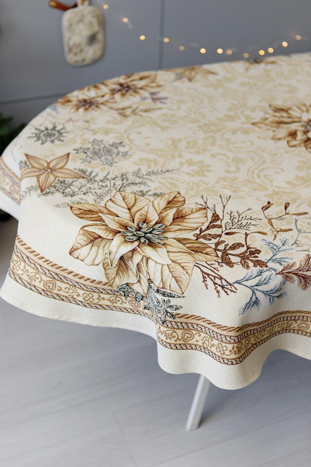 Oval woven tapestry tablecloth with Christmas poinsettia flower design. Beige and gold. Made in Ukraine.