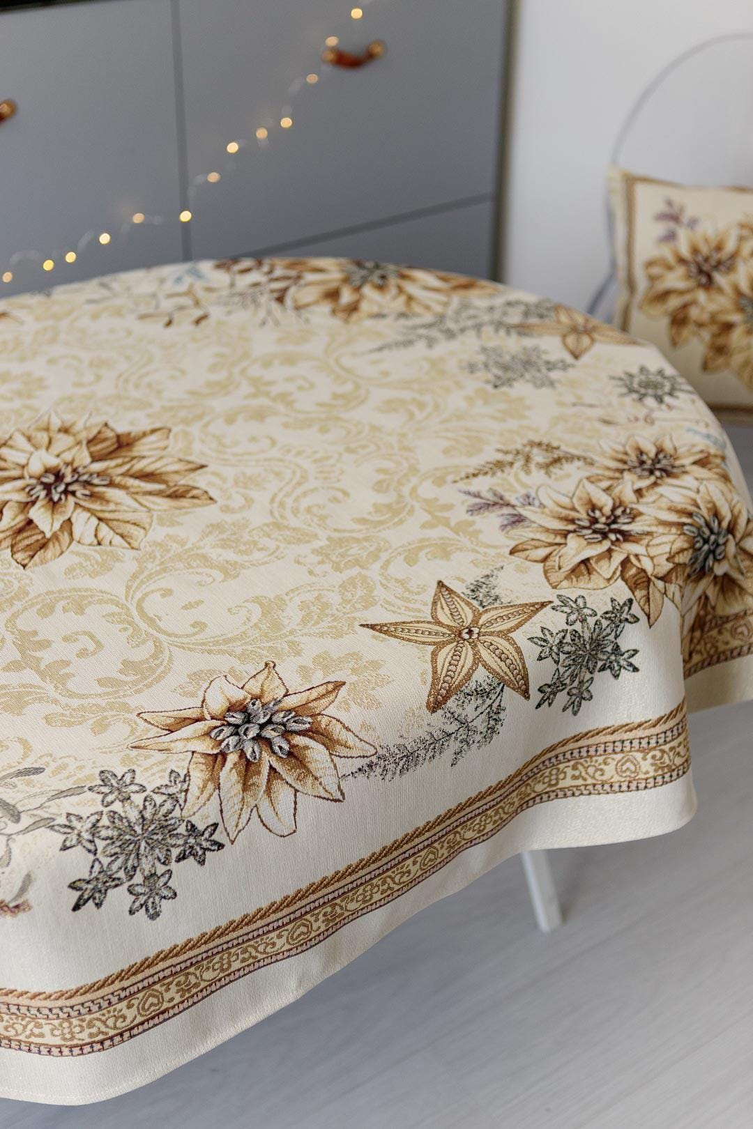Oval woven tapestry tablecloth with Christmas poinsettia flower design. Beige and gold. Made in Ukraine.