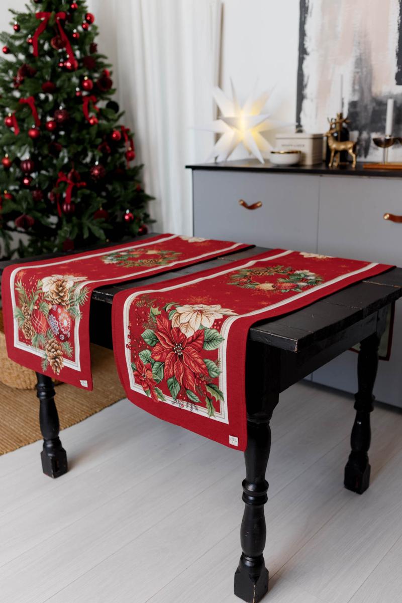 Red poinsettia Christmas tapestry table runner on a festive holiday dining table.
