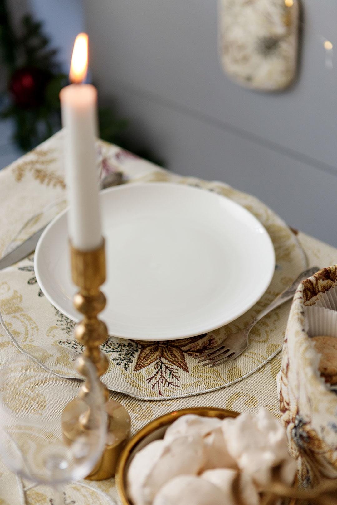 Round Christmas tapestry placemat with poinsettia floral design. Beige and gold festive holiday table decor.