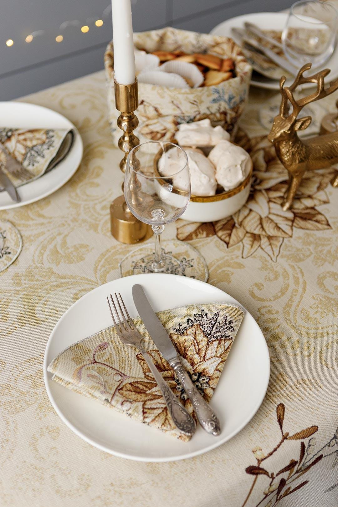 Round Christmas tapestry placemat with poinsettia floral design. Beige and gold festive holiday table decor.