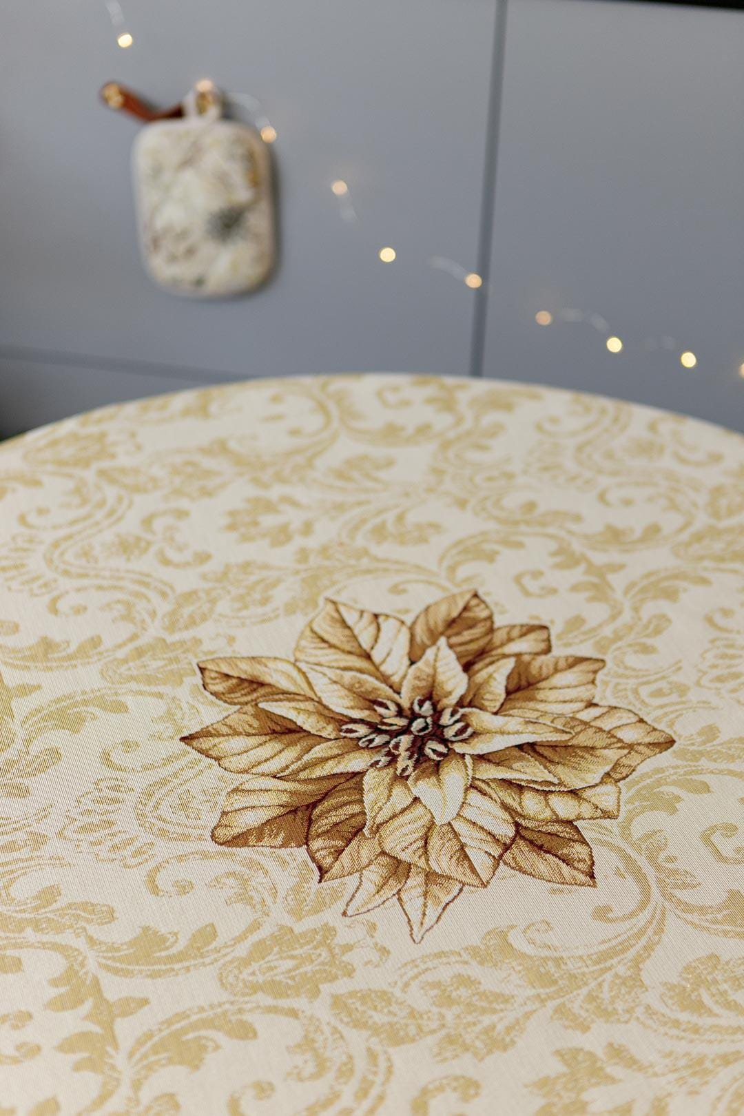 Round woven tapestry tablecloth with Christmas poinsettia flower design. Beige and gold. Made in Ukraine.