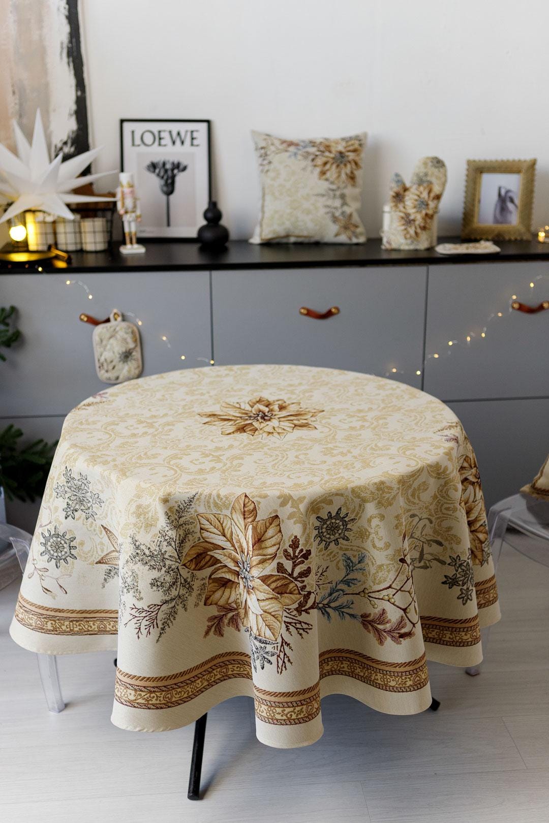 Round woven tapestry tablecloth with Christmas poinsettia flower design. Beige and gold. Made in Ukraine.