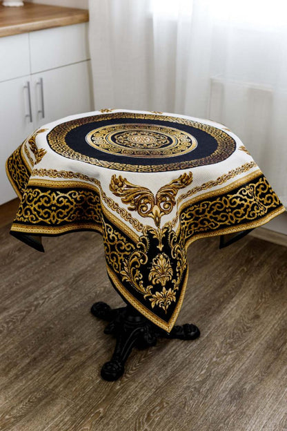 Square baroque tapestry tablecloth with gold medallion displayed on round table.
