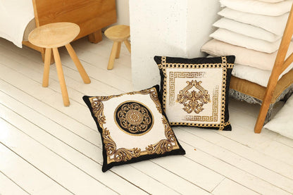 Two baroque tapestry pillows with gold patterns placed on a wooden floor in a cozy bedroom setting.