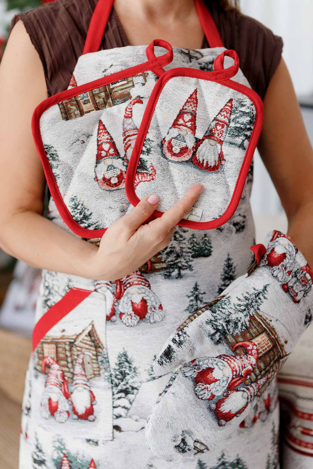 Woman holding matching Christmas gnome pot holders and oven mitt