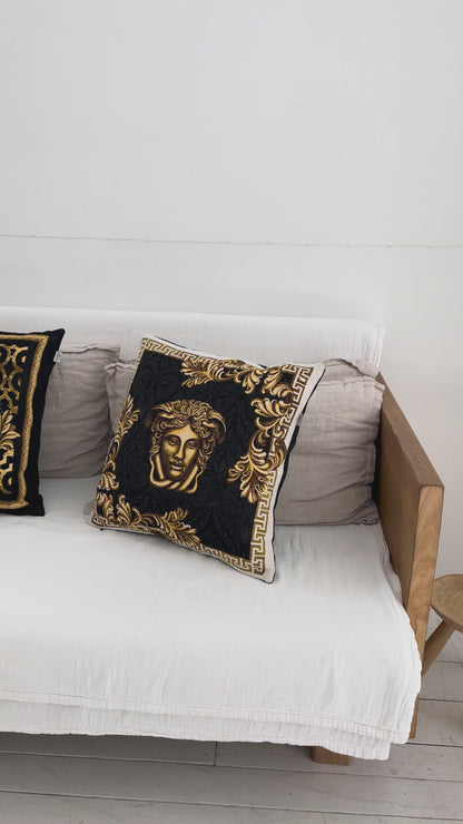 Black and gold baroque tapestry pillowcase with Medusa design styled on a white sofa in a luxury interior