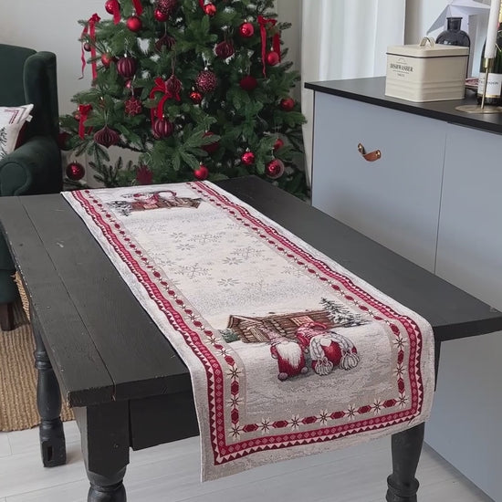 Video of Christmas table setup with gnome tapestry table runners on a rustic wooden table next to a decorated Christmas tree.