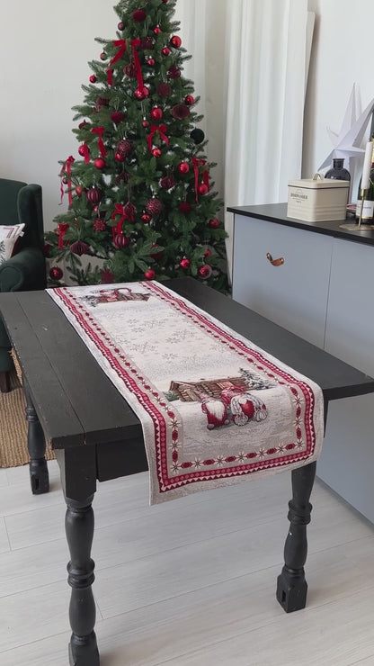 Video of Christmas table setup with gnome tapestry table runners on a rustic wooden table next to a decorated Christmas tree.